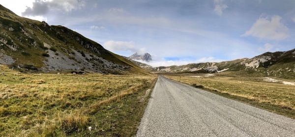 Road leading towards mountains against sky