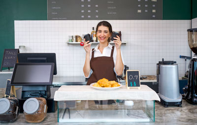Full length portrait of a smiling young woman holding food