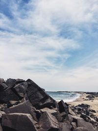 Idyllic view of beach against cloudy sky