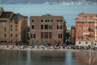 Group of people on boats in sea against buildings in city