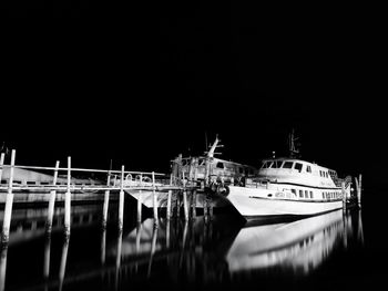 Boats moored at harbor against sky at night