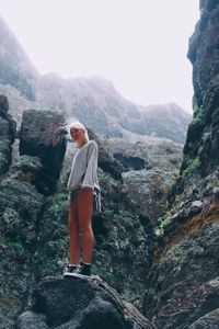 Low angle view of woman standing on mountain against clear sky