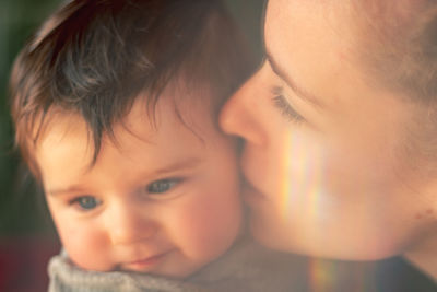 Portrait of mother kissing her baby