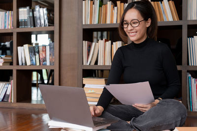 Woman using laptop while sitting on sofa at home