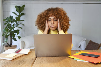 Young woman using mobile phone while sitting on table