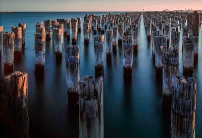 Panoramic view of wooden posts in sea against sky