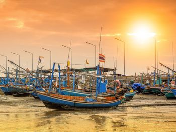 Boats moored at beach against sky during sunset