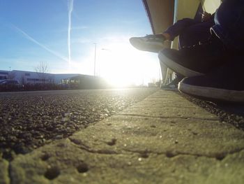 Low section of man on road against sky