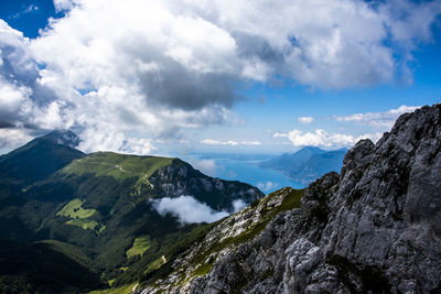 View of lake garda between rocks, clouds and blue sky on monte altissimo di nago in trento, italy