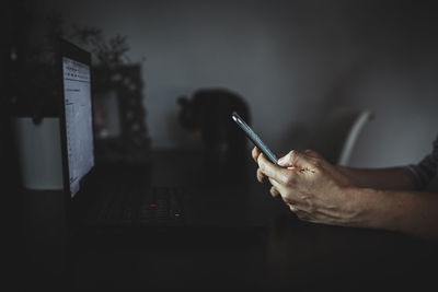 A woman works remotely from her home with a laptop and her phone.