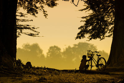 Silhouette trees on field against sky during sunset