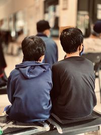 Rear view of people sitting on chairs waiting to be called