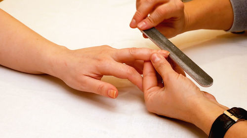 Cropped hands of woman filing female customer on table