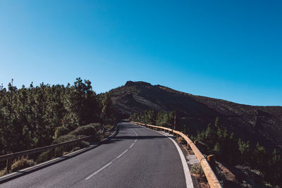 Empty road against clear blue sky