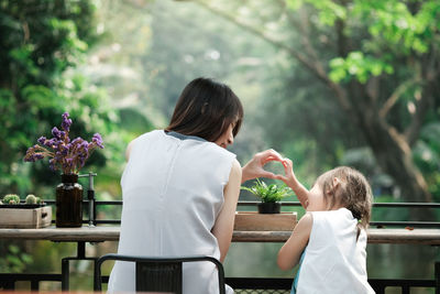 Rear view of mother and daughter on plants