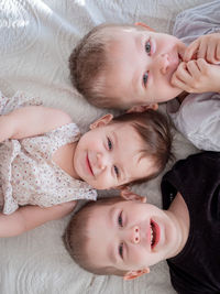 Directly above portrait of kids lying down on bed at home