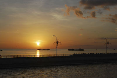 Silhouette ships sailing in sea against sky during sunset