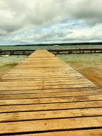 Wooden pier leading towards sea against sky