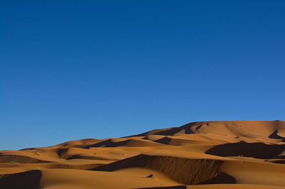 Scenic view of desert against clear blue sky