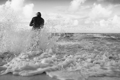 Man surfing in sea against sky