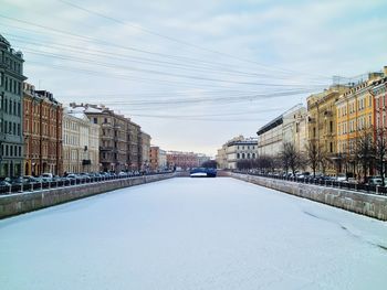 Road amidst buildings in city against sky