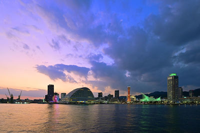 City at waterfront against cloudy sky