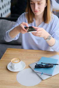 Girl taking photo of coffee cup and diary for social media