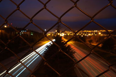 Full frame shot of illuminated chainlink fence against sky at night