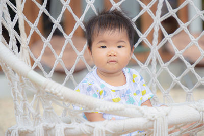 Portrait of cute baby girl looking through chainlink fence