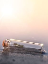 Close-up of bottle on beach against sky during sunset
