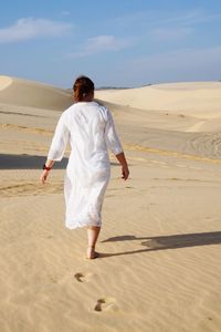 Rear view of man standing on sand dune