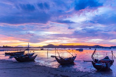 Boats moored on sea against sky during sunset