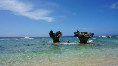 View of rocks in sea against blue sky