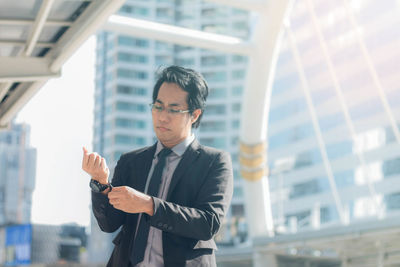 Close-up of businessman looking down against buildings