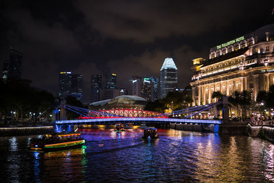 Illuminated bridge over river in city at night