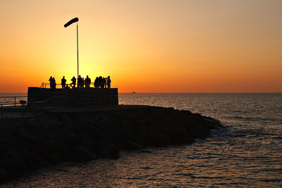 Silhouette people against calm sea