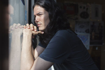 Portrait of a young man looking through a window