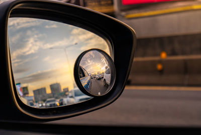 Reflection of traffic flow on asphalt road in side mirror of blue suv. car wing mirror.