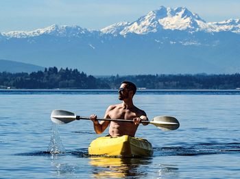 Man paddling kayak with mountains in background