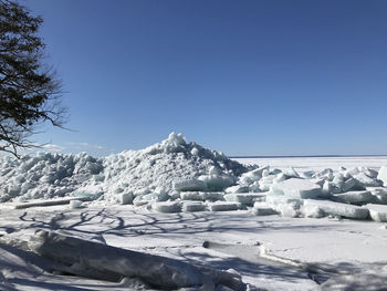 Snow covered landscape against clear blue sky