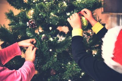 Children decorating christmas tree at home