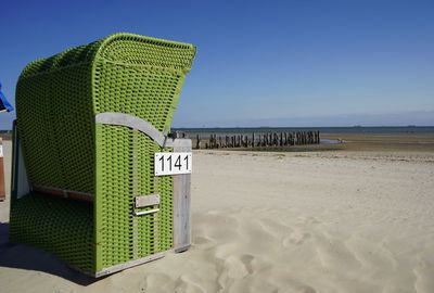 Hooded chairs on beach against clear sky