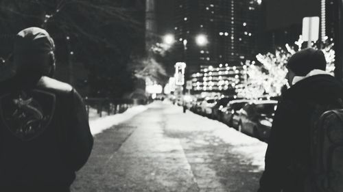 Rear view of woman walking on road in city at night