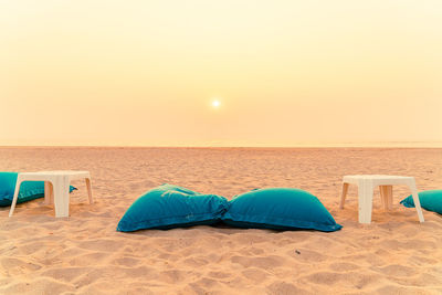 Blue umbrella on beach against sky during sunset