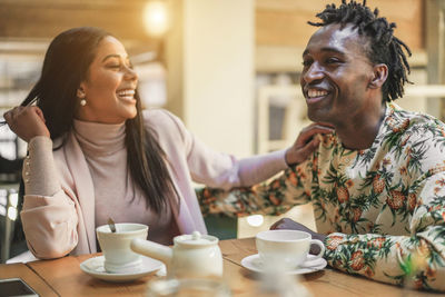 Smiling couple with coffee on table sitting in cafe