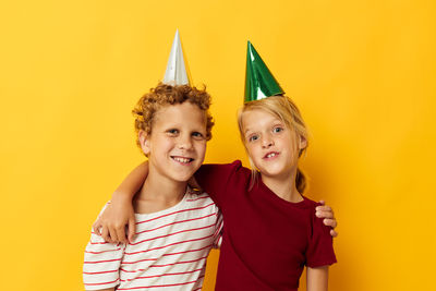 Portrait of sibling against yellow background