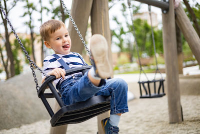 Boy playing on swing at playground