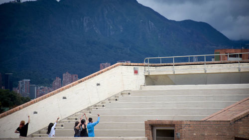 People standing by staircase against mountains