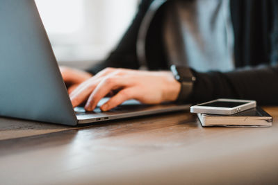 Close-up of woman using laptop on table