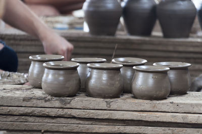 Cropped image of hand by clay pots in workshop